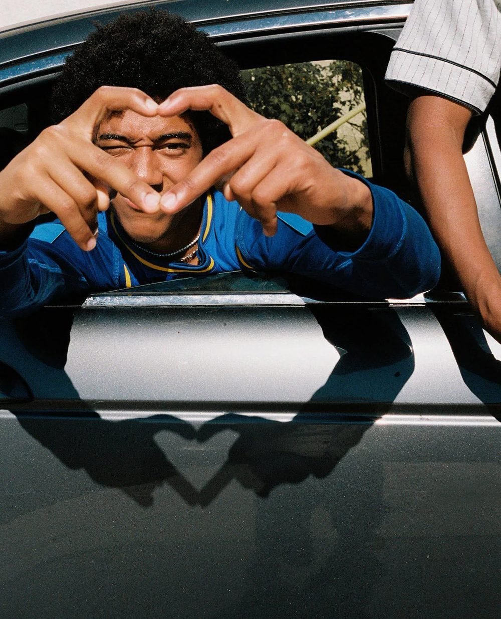 Chico haciendo un corazón con las manos desde un auto